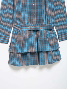 Détail de la robe à carreaux bleus avec ceinture à boucle et ourlet à volants