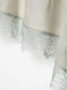 Close-up of silky satin fabric with delicate eyelash lace hem in silver champagne hue