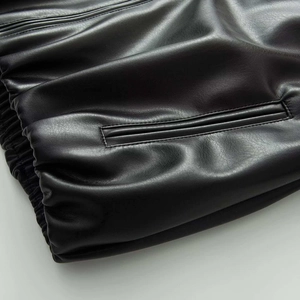 Detailed close-up of matte black leather jacket with welt pocket and ribbed cuff stitching