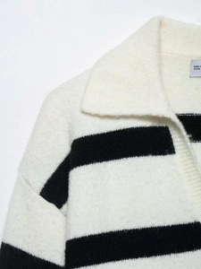 Detail of V-neck collar and black stripes on soft cream knit sweater texture