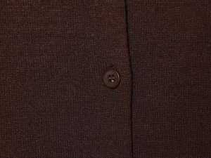 Detailed macro view of dark brown knitted fabric texture and matching round button closure