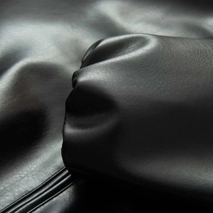 Macro shot of matte black leather texture with fine grain and soft sheen on the sleeve cuff
