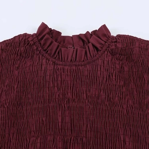 Detailed close-up of burgundy ruffle mock neck with elegant smocked texture and button