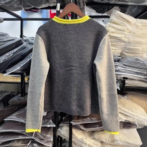 Vista posteriore di un cardigan in maglia grigia con bordi gialli e maniche bicolore