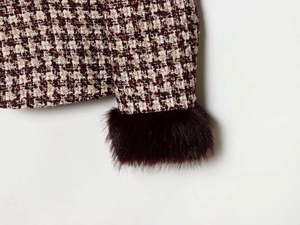 Detail of tweed blazer cuff featuring burgundy faux fur and classic houndstooth weave texture