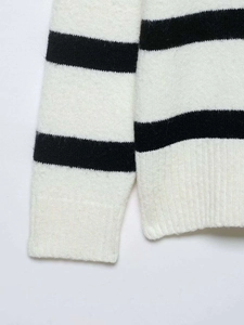 Detailed close-up of ribbed cuffs and hem on a black and white striped knit sweater