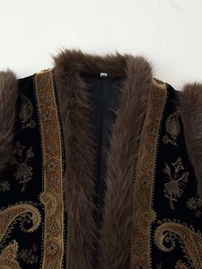 Detailed close-up of velvet vest featuring golden paisley embroidery and plush faux fur collar
