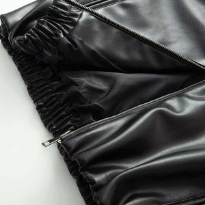 Detailed close-up of matte faux leather texture with zipper and elastic waistband