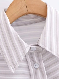 Detail of the classic pointed collar and grey striped fabric on a wooden hanger