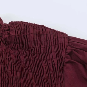 Close-up of the smocking detail and vertical texture on a burgundy cotton shirt