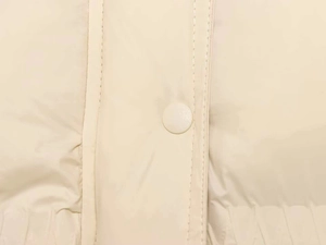 Detail of a beige puffer jacket showing a snap button fastener and double stitching