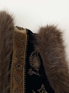 Close-up of vintage black velvet vest featuring gold embroidery and faux fur trim