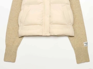 Detail of knitted sleeves and quilted vest with snap buttons on winter padded jacket