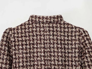Detail of tweed blazer texture with red and black weave and faux fur cuff finish
