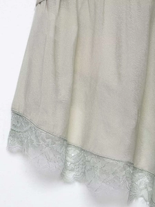 Close-up of sage green satin fabric with floral lace trim detail on the camisole hem