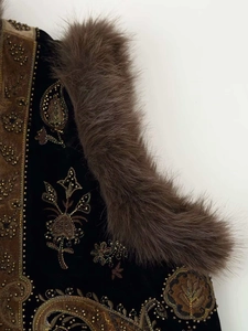 Detail of black velvet vest featuring luxury gold bead embroidery and plush fur trim