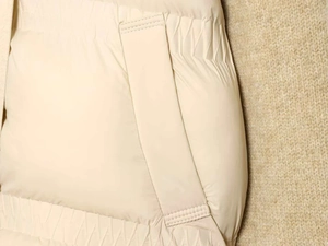 Detailed view of beige winter padded jacket showing neat stitching and pocket flap design
