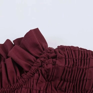 Detailed close-up of wine red textured fabric featuring elegant ruffles and smocking craft