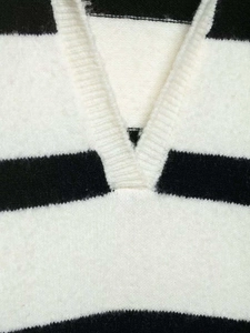 Close-up of the V-neckline detail on a black and white striped knit sweater