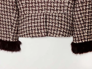 Detail of red tweed blazer sleeve featuring luxury faux fur trim and woven texture