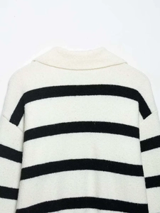 Detailed close-up of the knitted texture and V-neckline of a black and white striped sweater