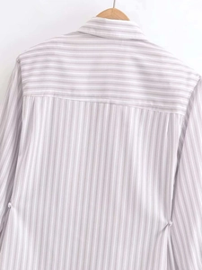 Detail view of a light gray and white striped shirt featuring horizontal yoke stitching