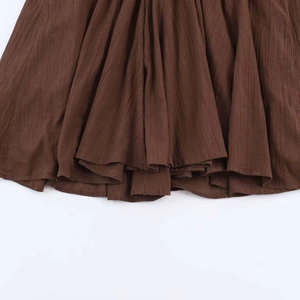 Detail showing the deep brown crinkled plisse fabric texture of the midi dress hemline