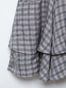 Detail of grey plaid layered hem on a mini dress with subtle textured fabric weave