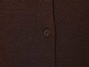 Detailed macro view of dark brown textured knit fabric and a matching four-hole button