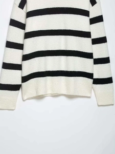 Detail of ribbed hem and texture on a black and white striped knitted sweater