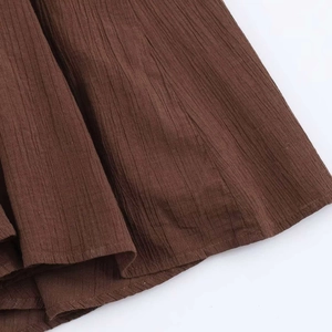 Detail of coffee brown midi dress showing crinkled fabric texture and fine hem stitching