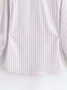 Detailed macro view of the curved hem and light pink vertical stripes on woven shirt