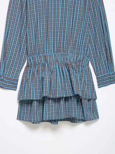 Détail de robe à manches longues à carreaux bleu et marron avec ourlet volanté à double couche