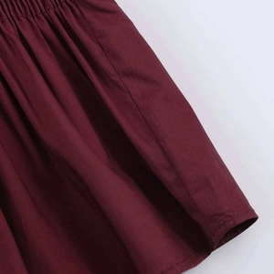 Detail view of burgundy pleated dress featuring an elastic waistband and soft fabric folds