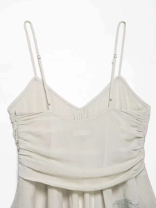 Detail view of the V-neckline with pleated ruching and adjustable straps on the camisole