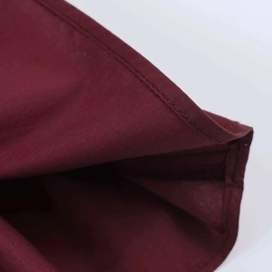 Macro shot of fine hem stitching on a burgundy honeycomb textured summer shirt