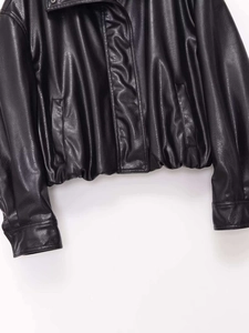 Detailed close-up showing the smooth black faux leather texture and stitching of a cropped jacket