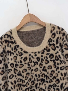Detail of round neck leopard print knit sweater with ribbed neckline on wooden hanger