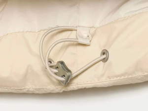 Macro view of adjustable elastic drawstring and toggle on beige winter jacket hem