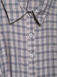 Close-up of checkered shirt collar and translucent white buttons on woven fabric