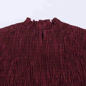 Detailed macro view of wine red smocked fabric with a ruffled stand collar and back slit detail