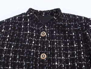 Macro detail of black tweed jacket featuring golden lion-embossed metal buttons
