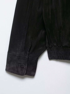 Detailansicht der schwarzen Wildlederjacke mit geknöpften Ärmeln und elastischem Saum