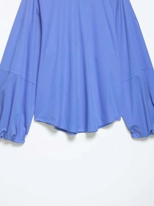 Detailansicht des geschwungenen Saums und der Laternenärmel an dieser helllila Bluse