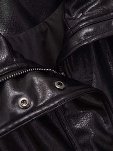 Close-up of pebble-grain black leather jacket collar with silver snaps and metal zipper
