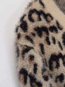 Close-up detail of soft leopard print knit fabric with fluffy faux fur texture