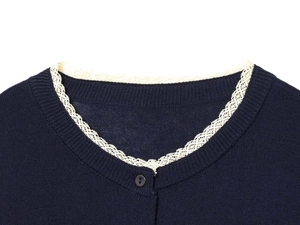 Detailed view of dark blue knit cardigan collar with white lace trim and black button