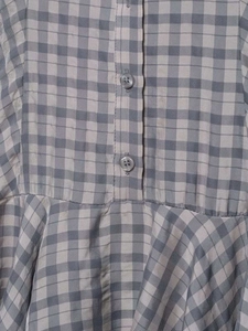 Close-up of grey plaid summer dress showing translucent buttons and pleated fabric texture