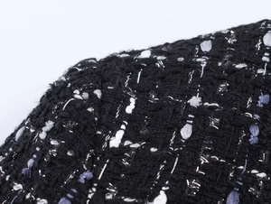Close-up of black and white tweed fabric texture with metallic thread weaving detail