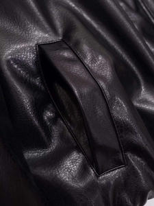 Close-up of black faux leather jacket showing fine texture and side pocket stitching